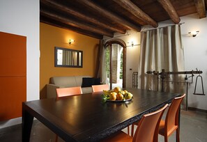 A dining area with a wooden table, orange chairs, and a bowl of lemons. There is a sofa and a mirror on the wall. - Villa Moro Lin (Mestre)