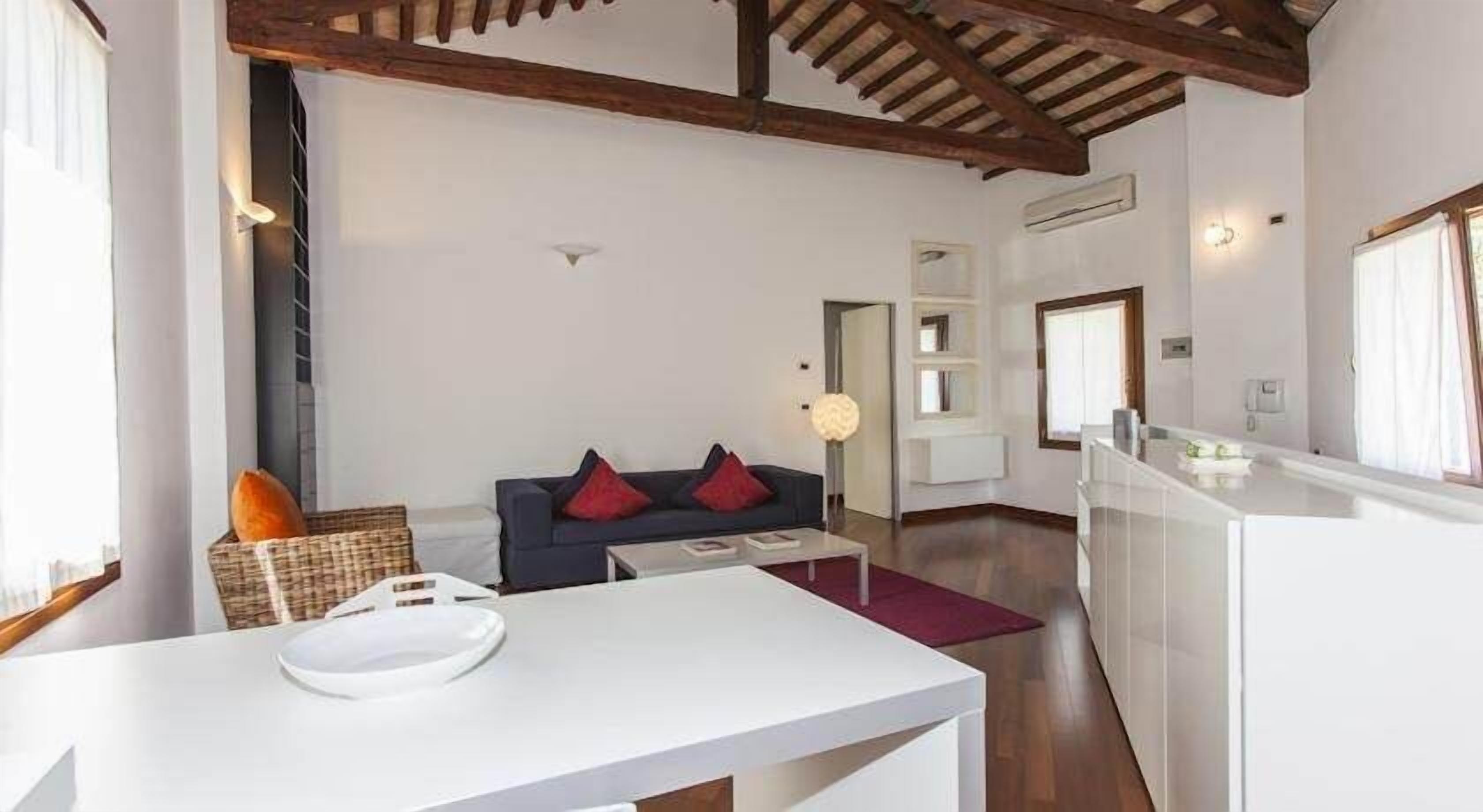 Un salon moderne avec un canapé, une table basse et un coin repas comprenant une table et des chaises blanches.