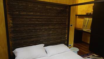 Un dormitorio con cama, cabecera de madera y una mesita de noche con espejo.