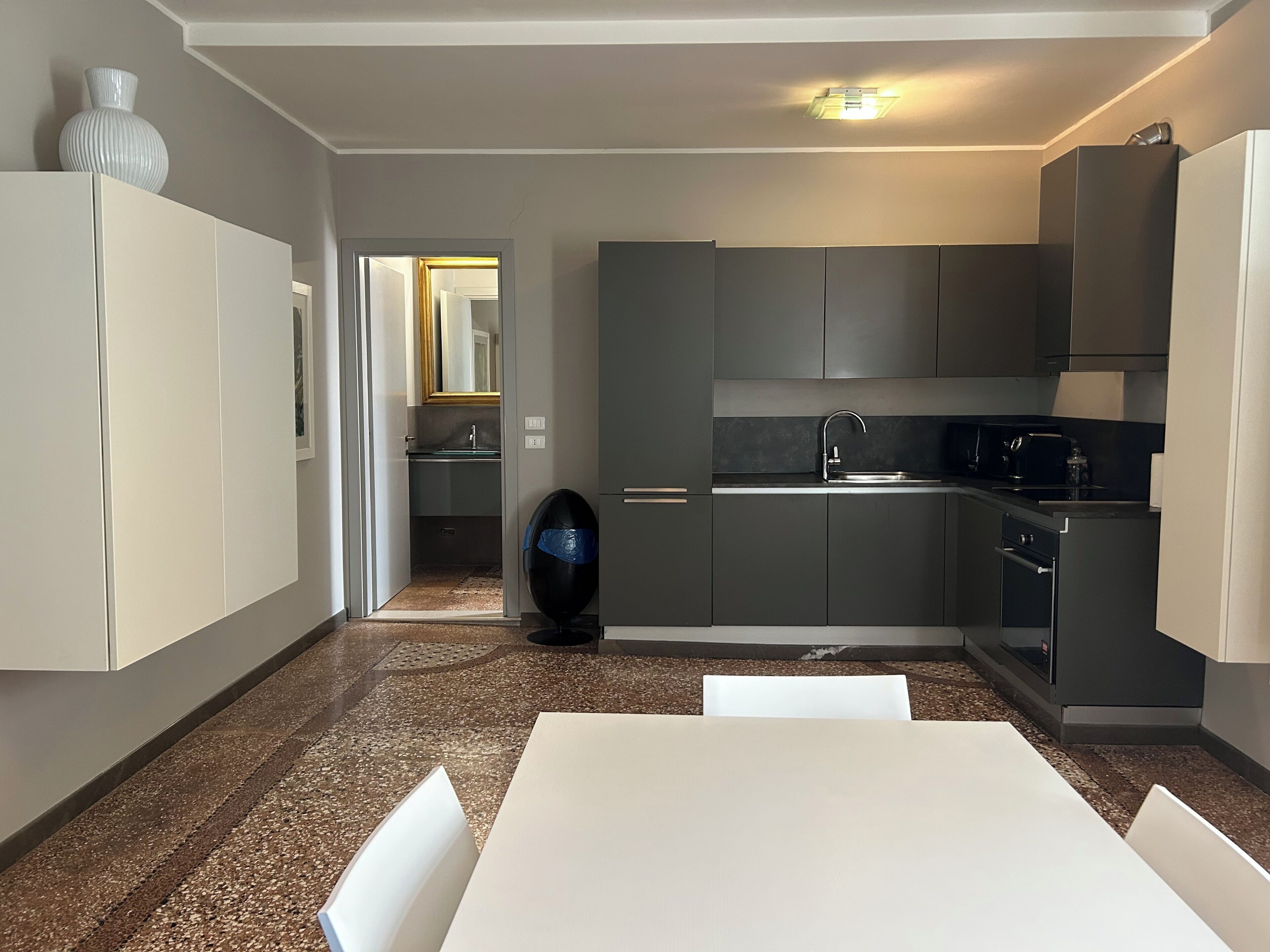 A modern kitchen with dark cabinets, a white countertop, and a dining area with a table and chairs.