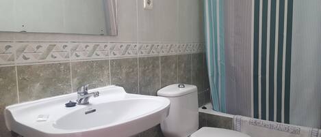 A bathroom with a white sink, toilet, and a striped shower curtain.