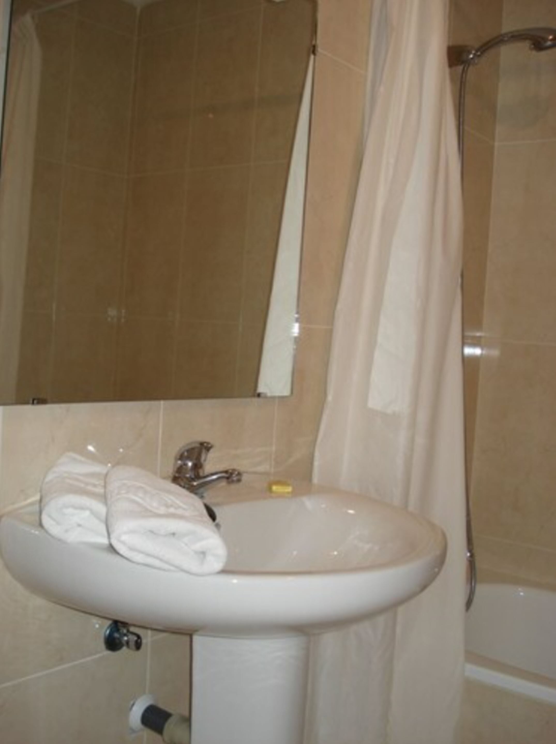 A bathroom with a sink, mirror, and shower curtain.