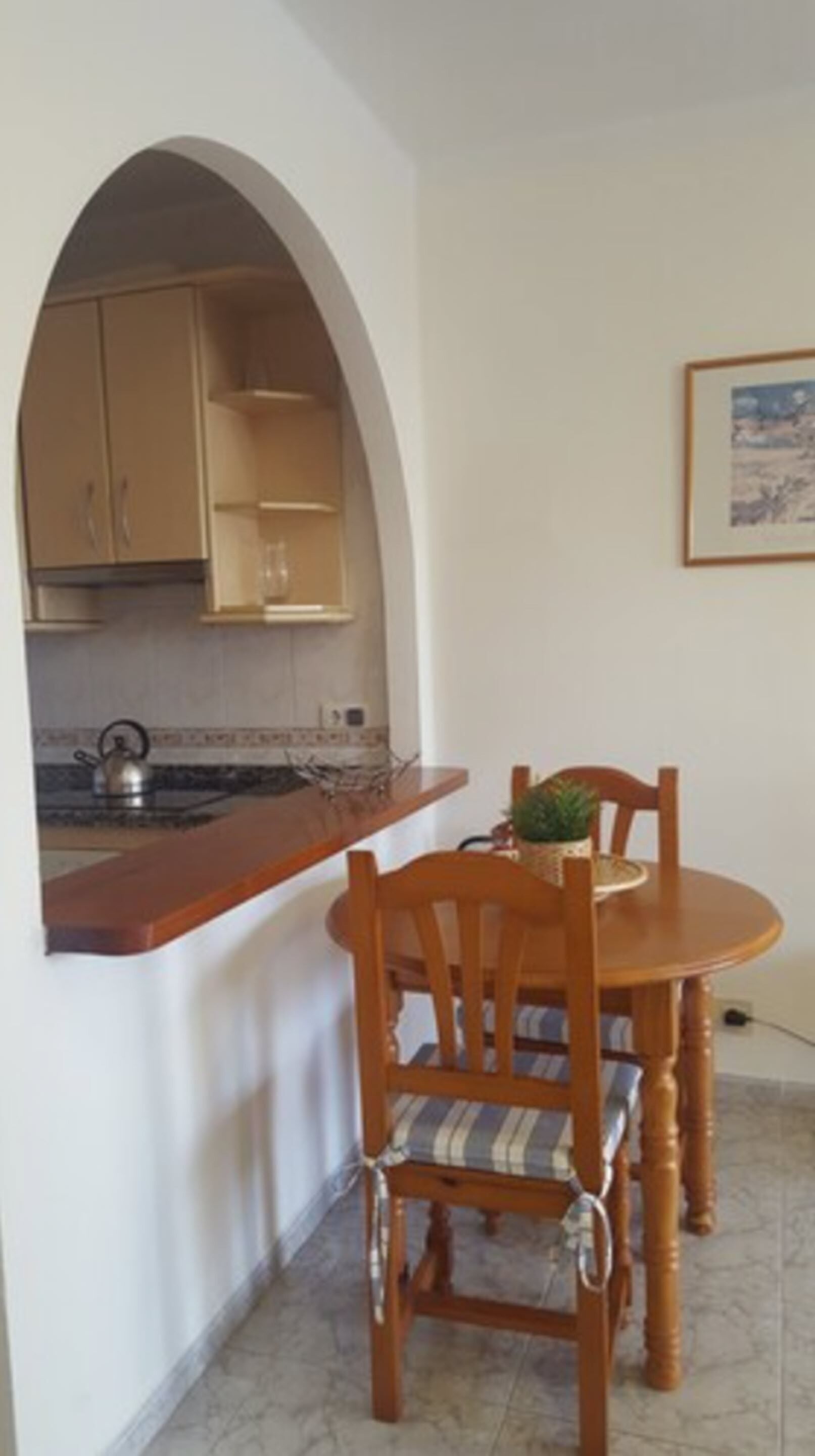 A compact kitchen with an archway leading to a dining area.