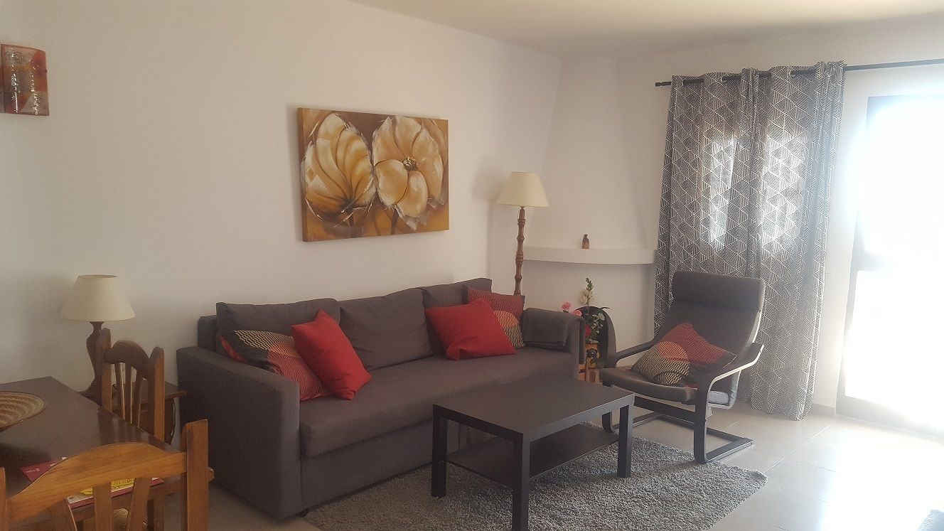 A living room with a sofa, armchair, coffee table, and lamps.