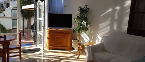 Una sala de estar con televisor, sofá, mesa de centro y mesa de comedor.