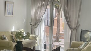 A living room with a sofa, armchairs, a coffee table, and a TV. - Apartamentos Puerto Sherry (El Puerto de Santa Maria)