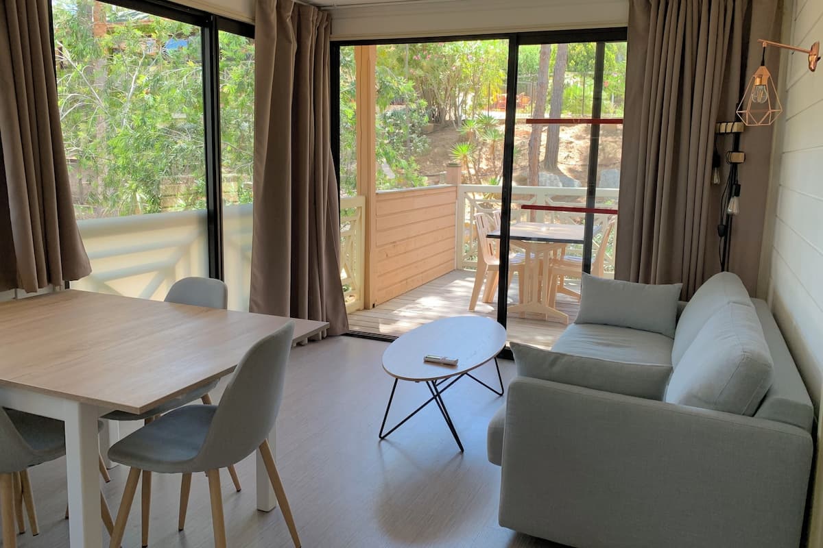 A modern room with a wooden table, grey chairs, a white sofa, and a small round table.