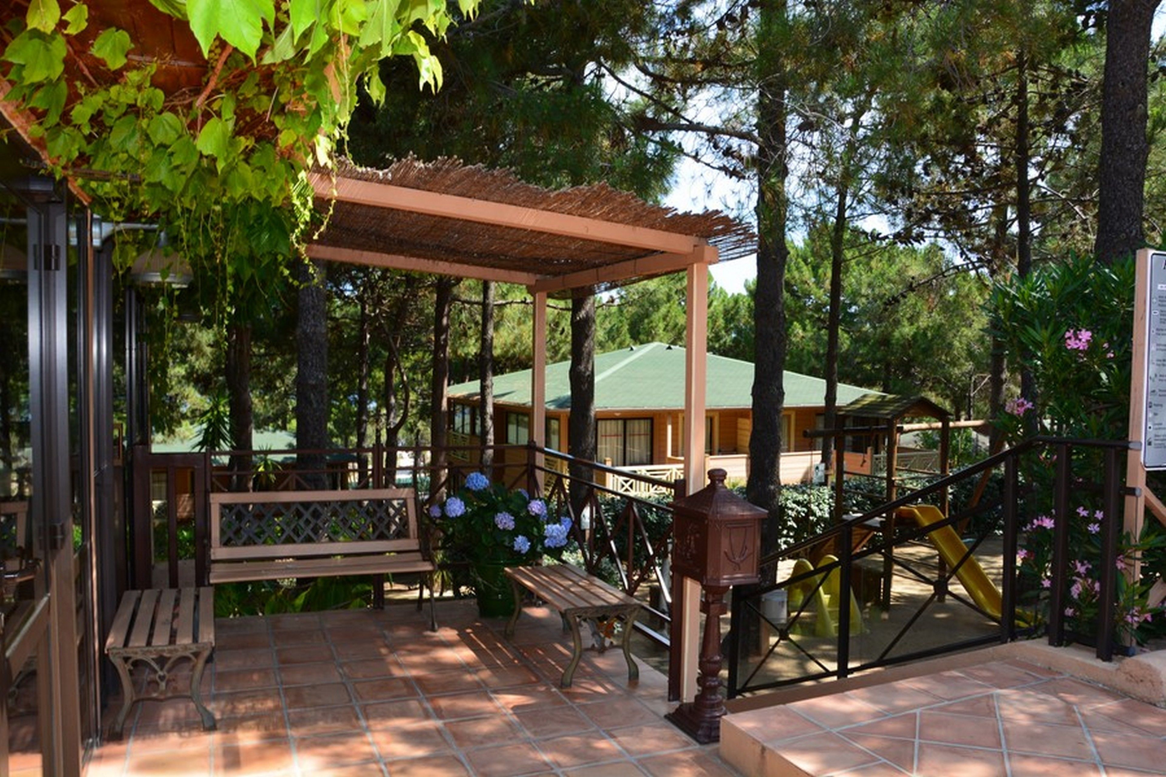 A covered outdoor area with benches, a pergola, and a playground.
