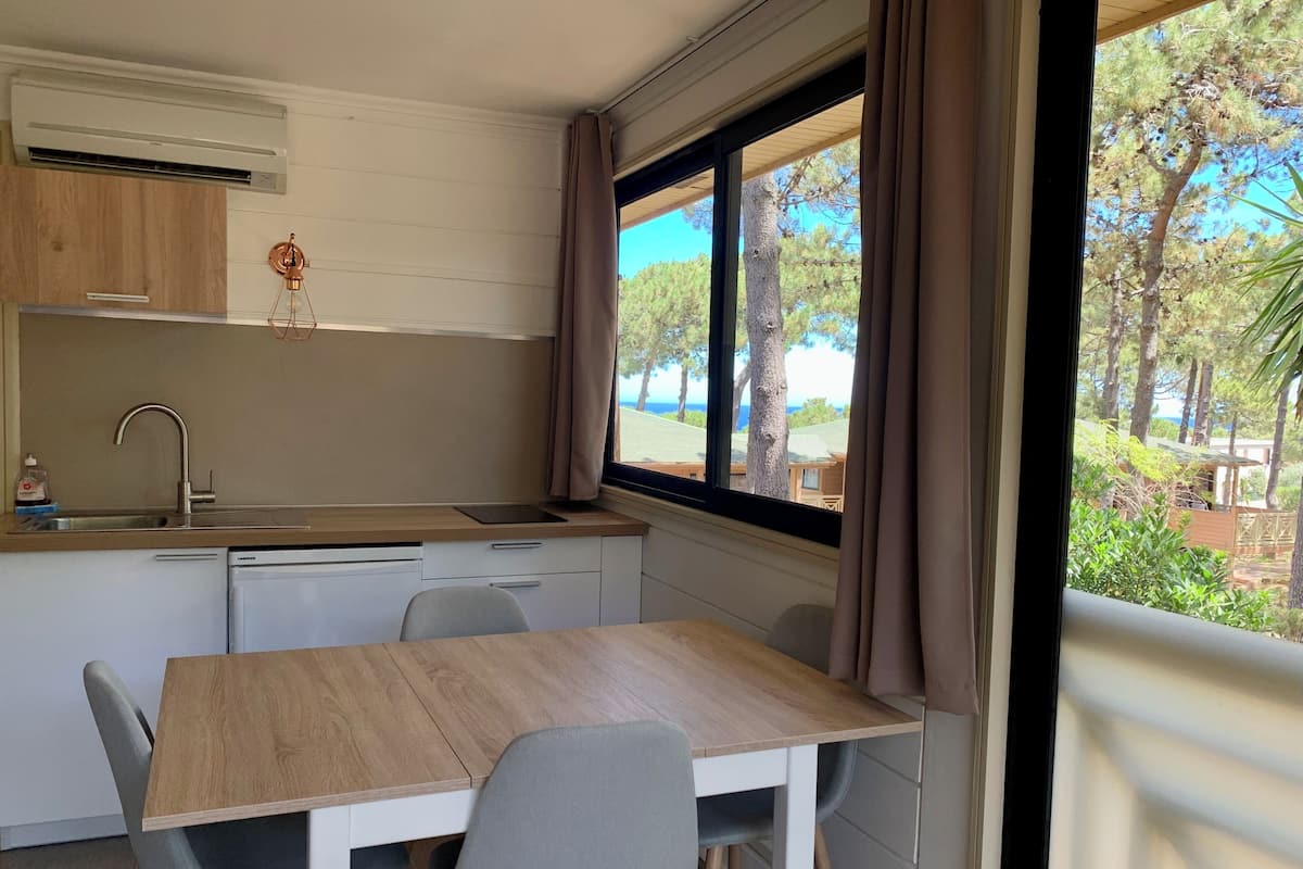 A compact kitchenette with a sink, a small countertop, and a window overlooking a garden.