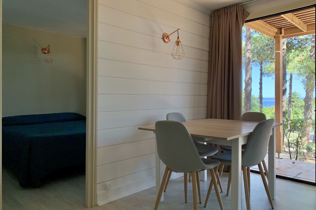 A dining area with a table and chairs, a blue sofa, and a view of the sea through large windows.