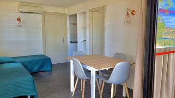Una habitació amb un llit, una taula, cadires, una porta i una finestra amb vistes.