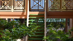 A wooden staircase leading to a covered area with a view of the ocean. - Résidence Les Pins (Calvi)