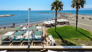 A beach with sun loungers, umbrellas, and palm trees. - Hotel La Chancla (Málaga)