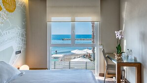 A hotel room with a bed, a desk, and a large window overlooking a beach. - Hotel La Chancla (Málaga)
