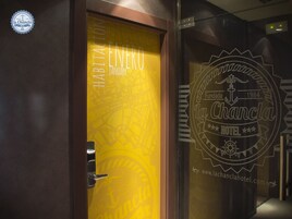 Entrada de un hotel con puerta de vidrio que muestra el nombre 'La Chanca' y el año '1984'.