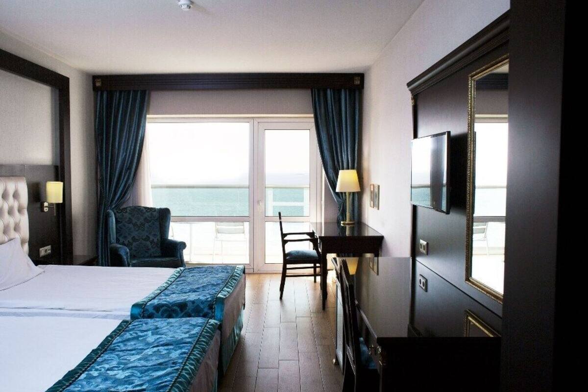 A hotel room with a large bed, two bedside tables, a desk, a chair, and a TV.