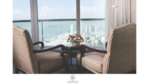 A high-rise room with a city view, two upholstered chairs, a small table with a vase of flowers, and a floor lamp. - Ege Palas Business Hotel (Izmir)
