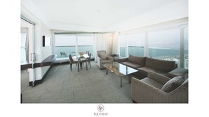 A modern hotel room with a balcony, a dining area, and a seating area with a view of the sea. - Ege Palas Business Hotel (Izmir)