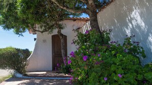 A building with a white exterior, a wooden door, and a tiled entrance. - AHR Altura Hotel Porto Rafael (Palau)