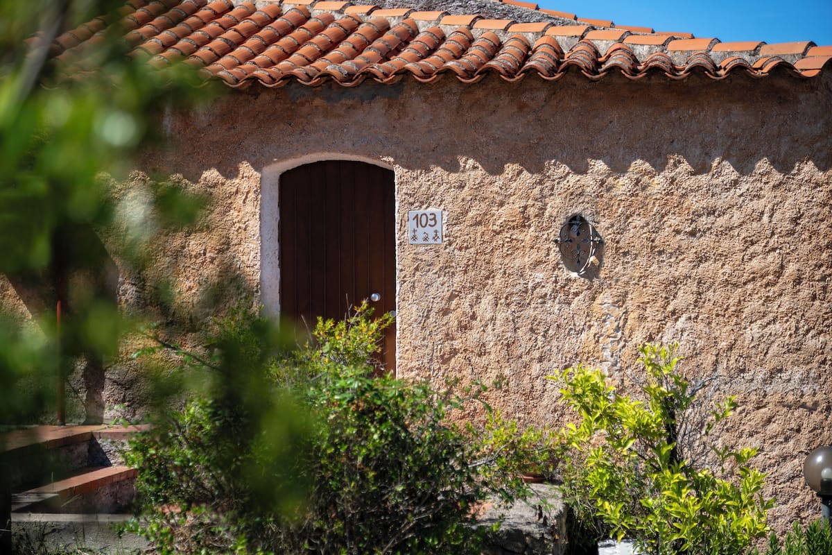 A rustic building with a tiled roof, a wooden door, and a stone wall.