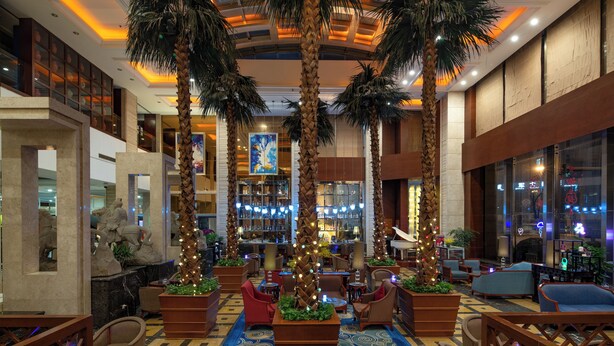 A lobby with palm trees, seating areas, and a bar. - Chengdu Tianfu Sunshine Hotel (Chengdu)