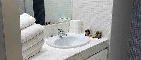 A modern bathroom with a white sink, a large mirror, and a shower area.