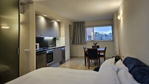 Una habitación de hotel moderna con kitchenette, comedor y una cama grande.