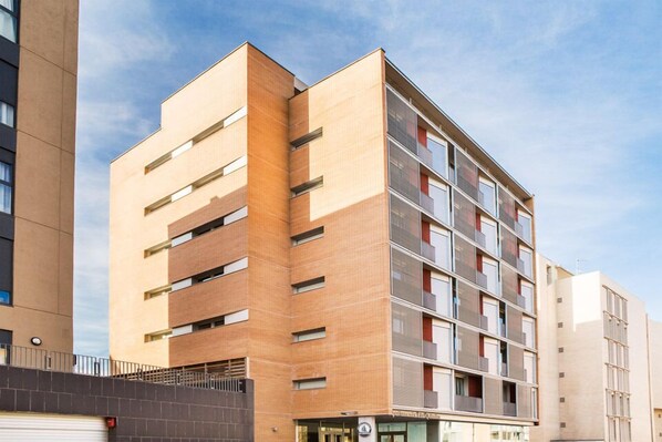 A multi-story hotel with a modern design, featuring a mix of brick and glass facades, and a visible ground-level entrance.