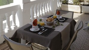 A table set for breakfast with a mountain view, white columns, and a red awning. - Le Château des Magnans (Jausiers)