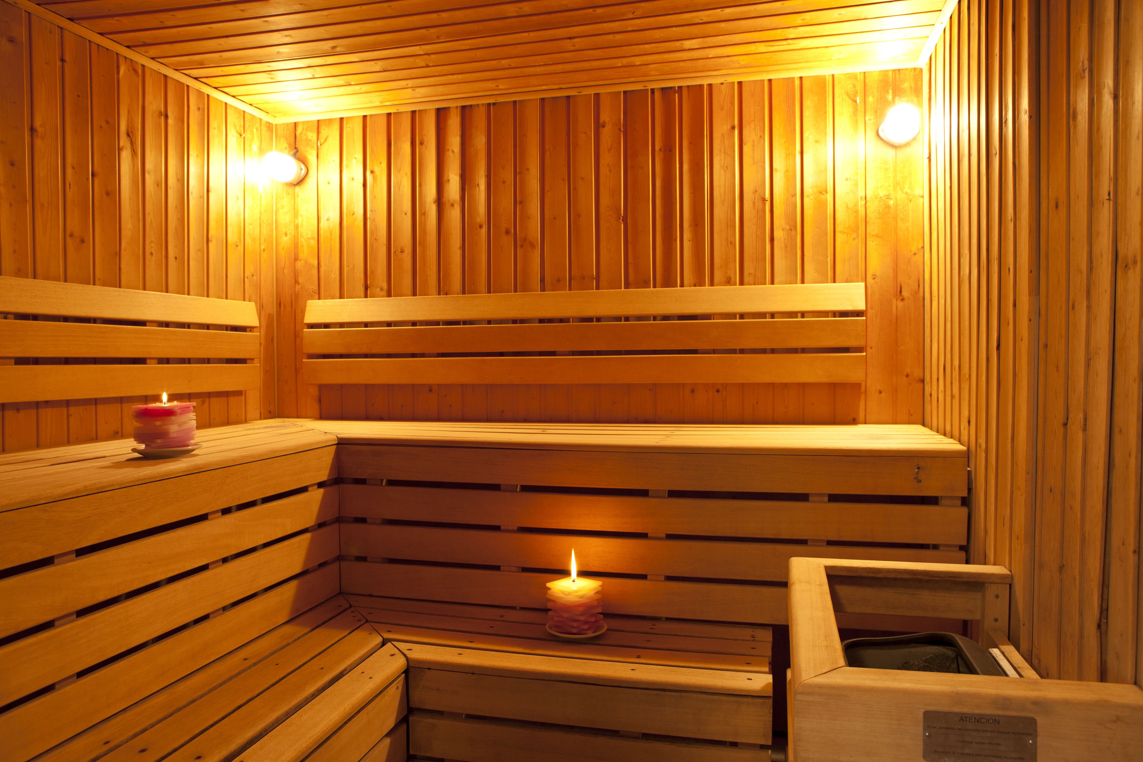 A wooden sauna with benches and a lit candle.