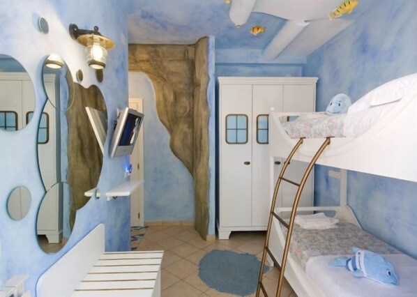 Une chambre d’enfant avec un lit superposé, une armoire, un bureau avec un ordinateur et un téléviseur fixé au mur.