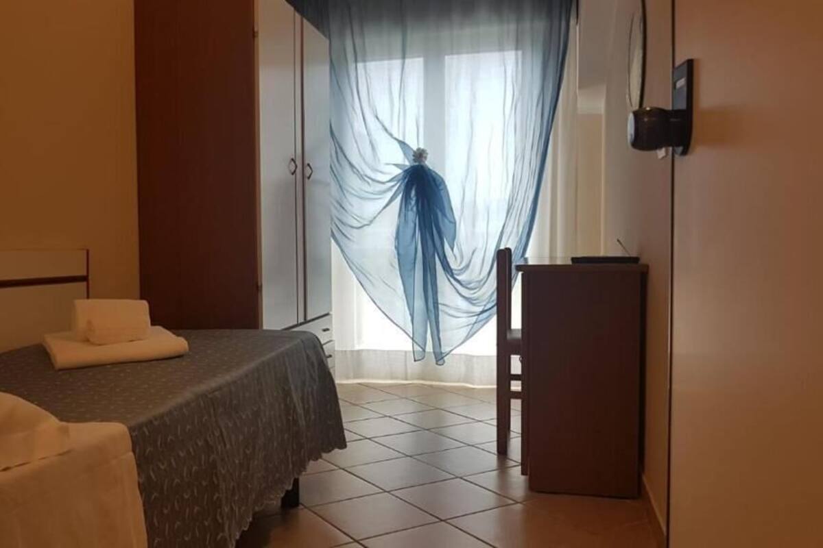 A hotel room with a bed, a desk, and a chair.