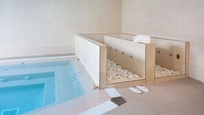 A modern spa area with a pool, a separate shower area with pebbles, and a towel rack. - Hotel Best Tenerife (Arona)