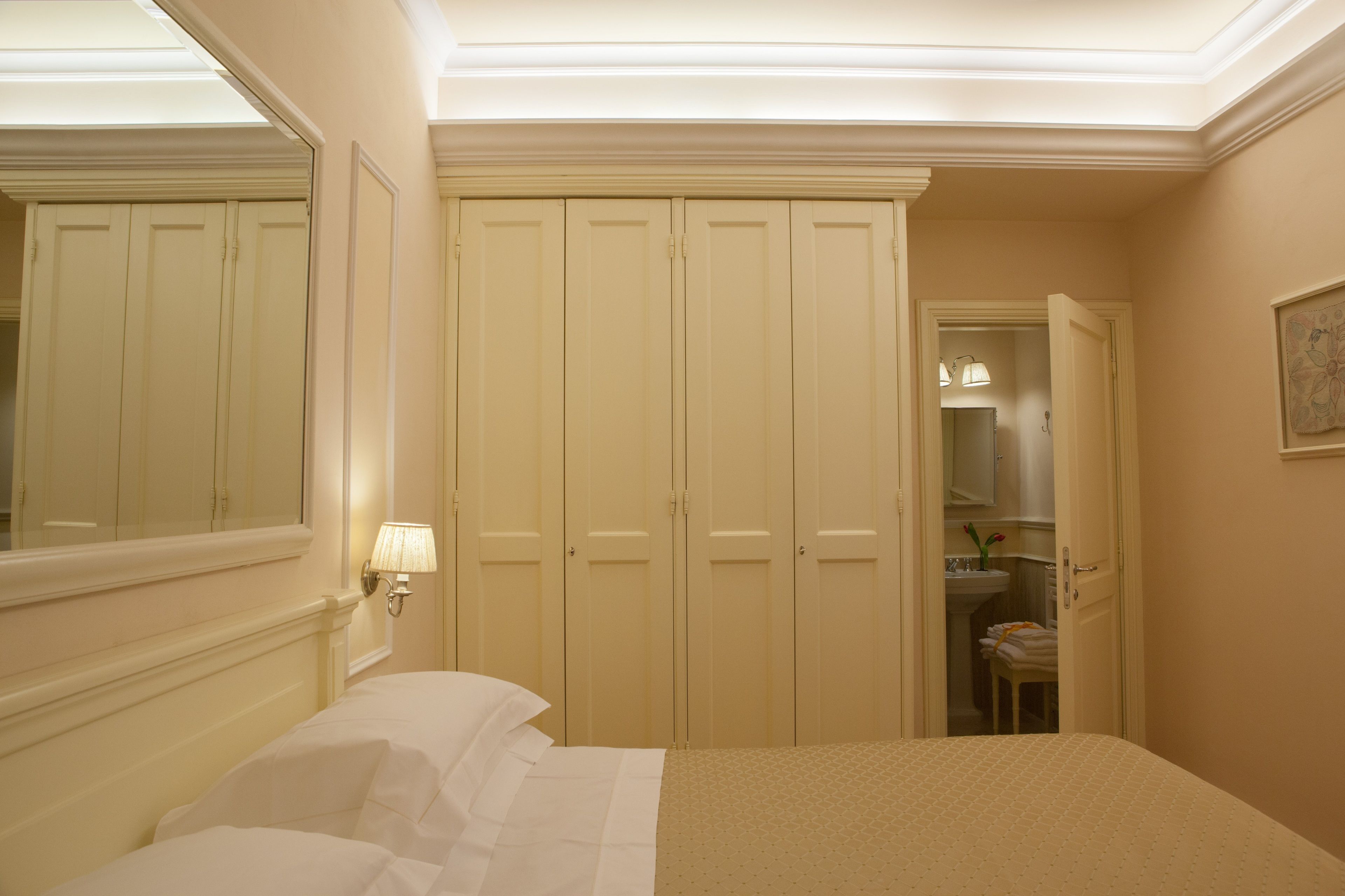 A bedroom with a bed, a wardrobe, and a bathroom visible through an open door.