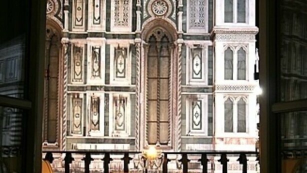 A room with a view of a historic building with ornate architecture, a wooden table, and two chairs. - Granduomo Charming Accomodation (Florence)