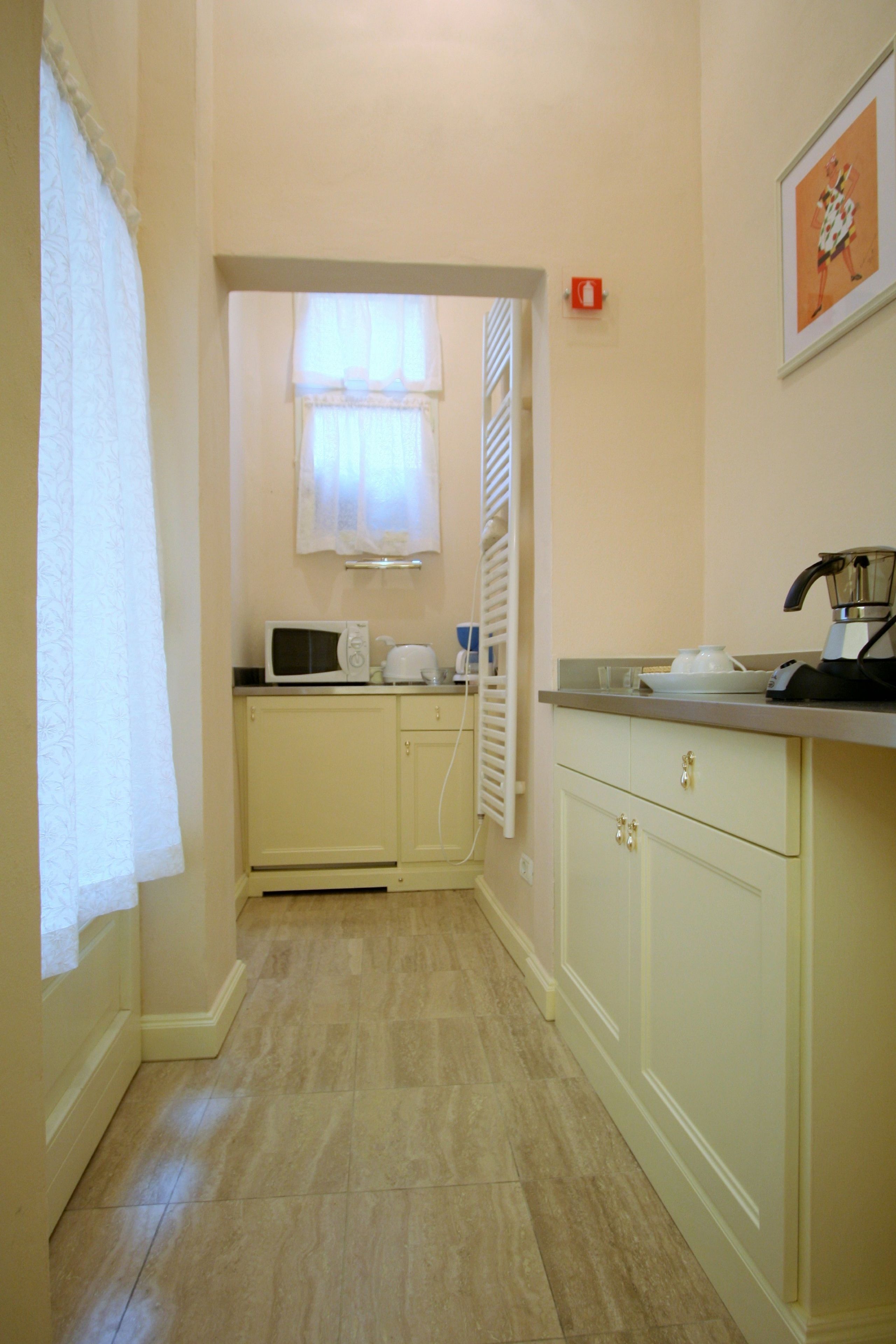 A narrow kitchen with a microwave, kettle, and coffee maker on the counter.