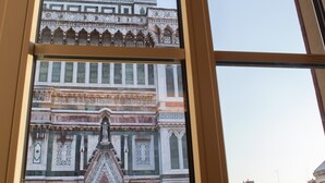 A view through a window of a building with intricate architectural details, including ornate facades and multiple levels. - Granduomo Charming Accomodation (Florence)