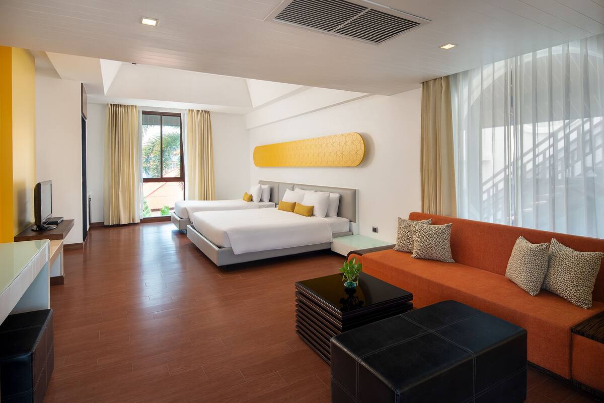 Quarto de hotel moderno com cama, sofá e escrivaninha.