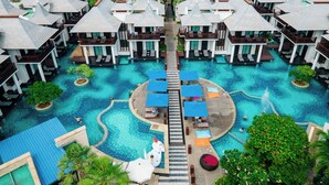 Un resort con varias cabañas sobre el agua, un área de piscina central y un puente que las conecta.