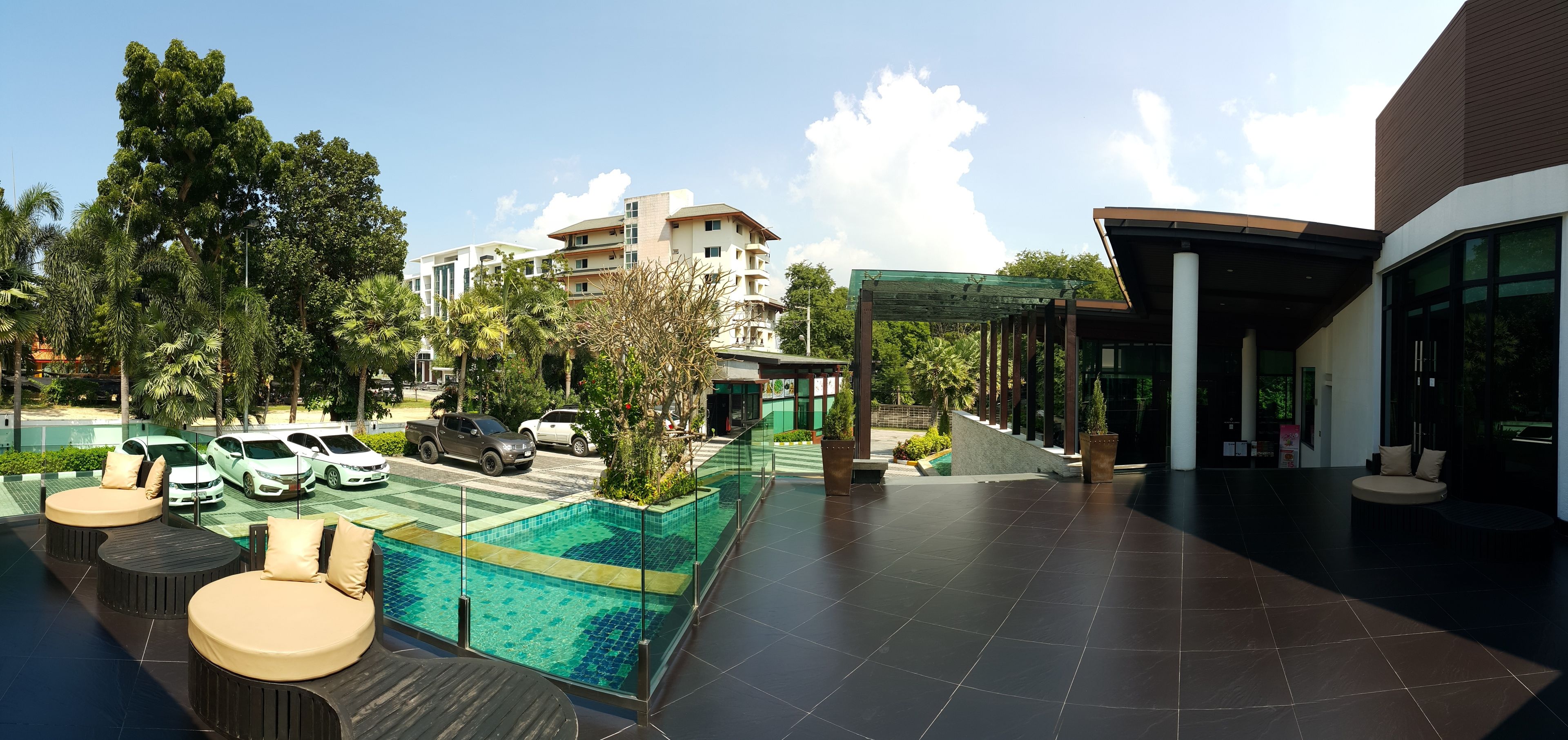 A rooftop pool area with lounge seating and a view of a multi-story building in the background.