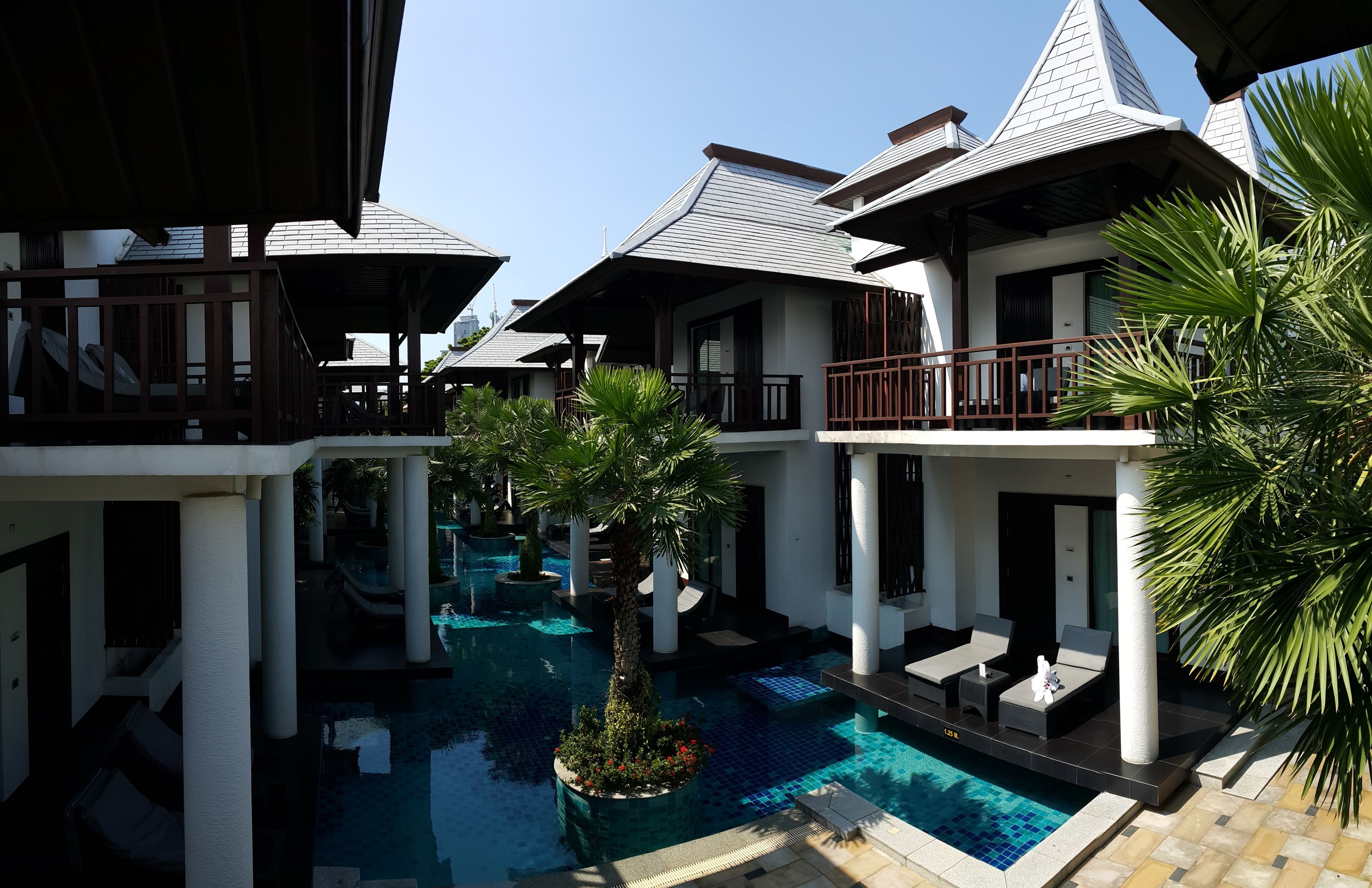 A resort with multiple buildings, a central swimming pool, and outdoor seating areas.