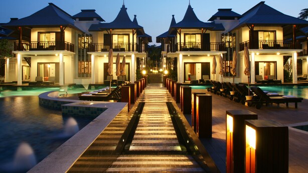 Un resort con varias construcciones, una piscina y un paseo que lleva al área de la piscina.