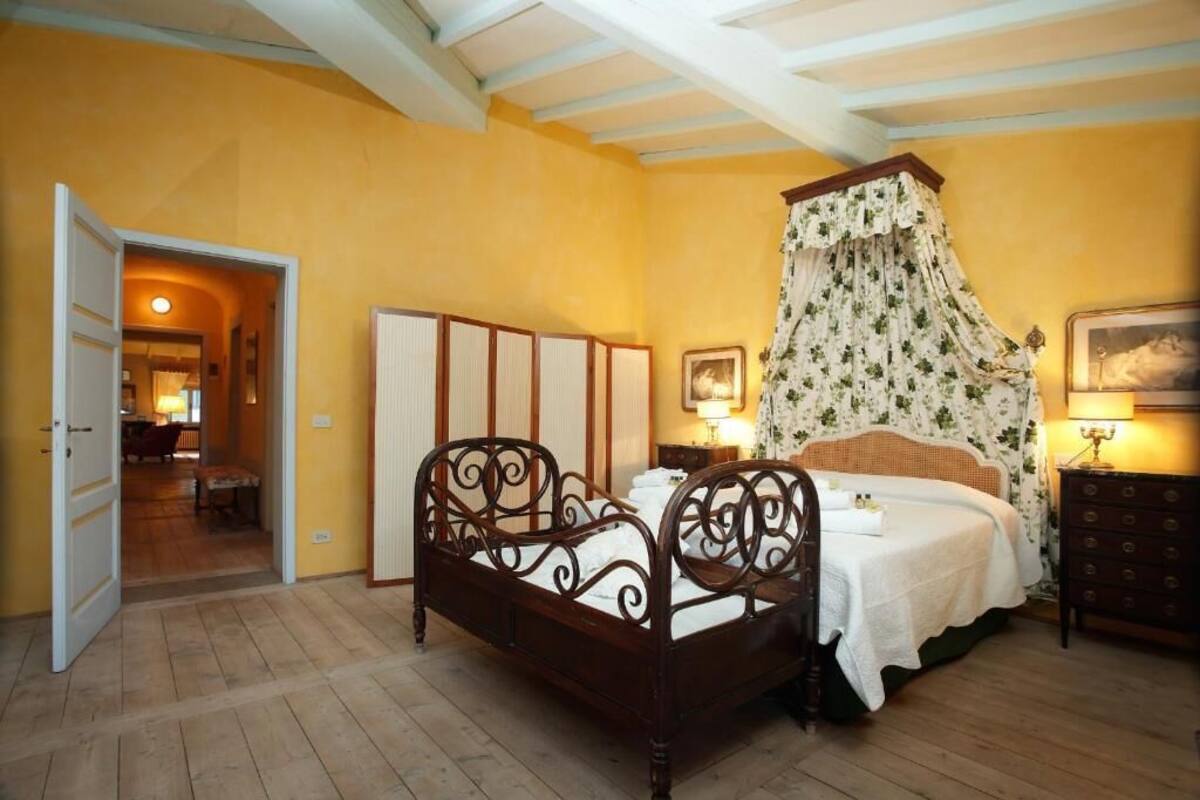 A bedroom with a wooden bed, a canopy bed, and a bedside table with a lamp.
