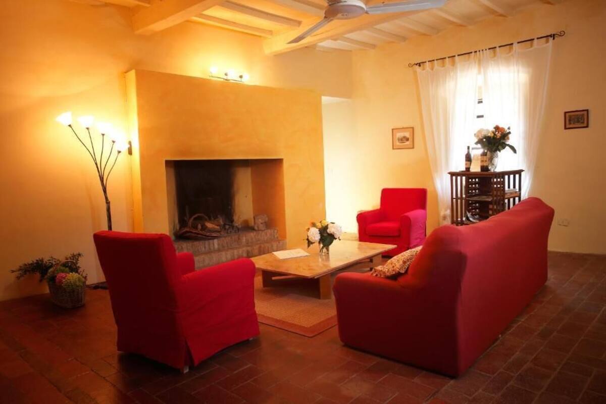 A living room with a fireplace, red furniture, and a ceiling fan.
