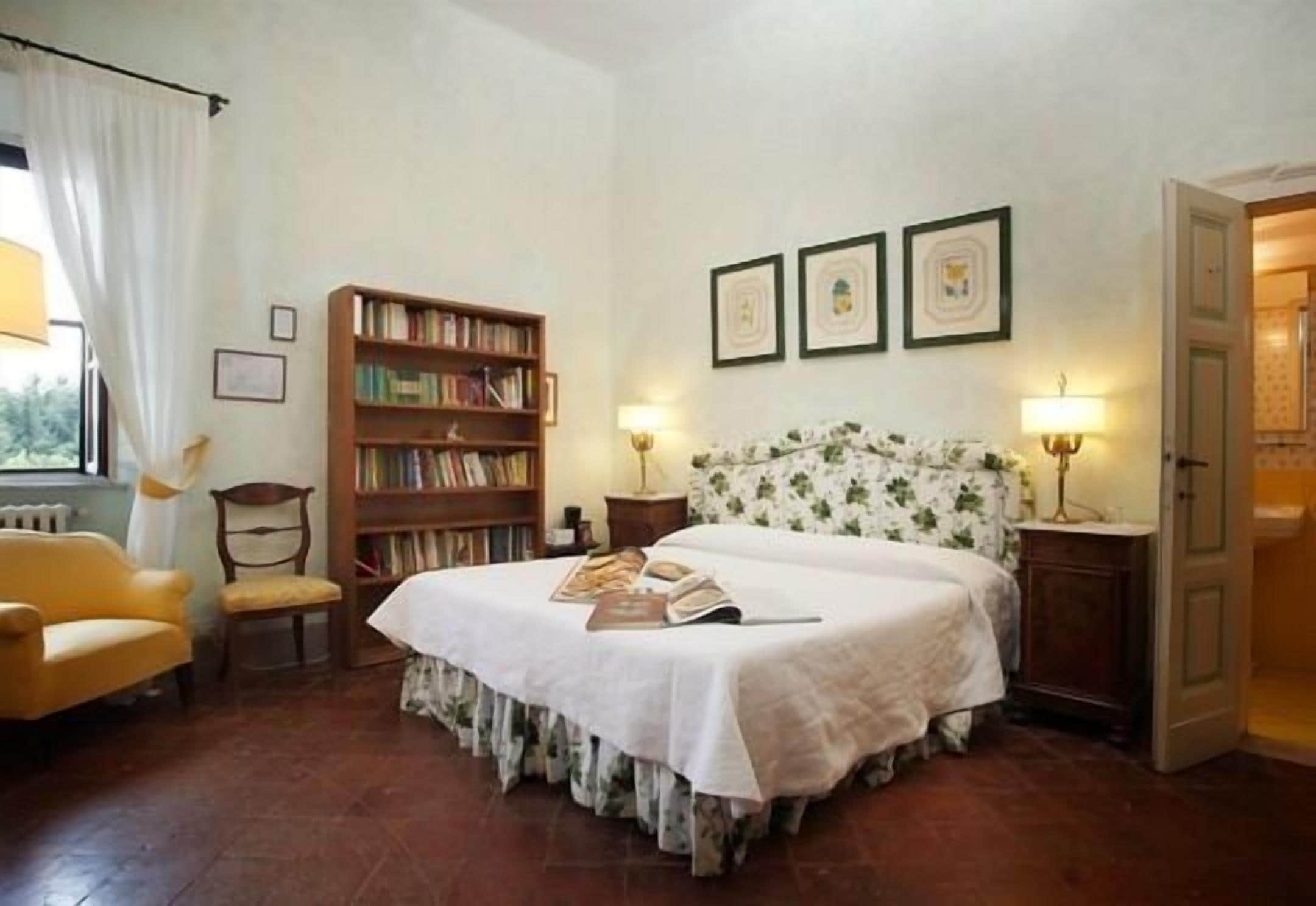 A bedroom with a bed, a bookshelf, a chair, and a door.