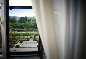 Vista de un jardín con setos cuidadosamente recortados y una fuente central.