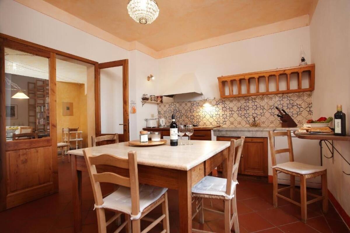 A kitchen with wooden cabinets, a tiled backsplash, and a dining area with a table and chairs.