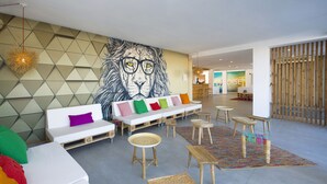 Un interior moderno con un gran mural en la pared, un sofá blanco con cojines de colores y una zona de asientos con banco de madera.