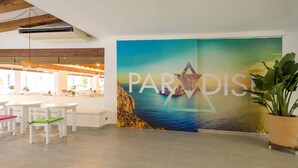 Un interior moderno con un letrero grande que dice 'PARADISE', muebles blancos y una planta en maceta.