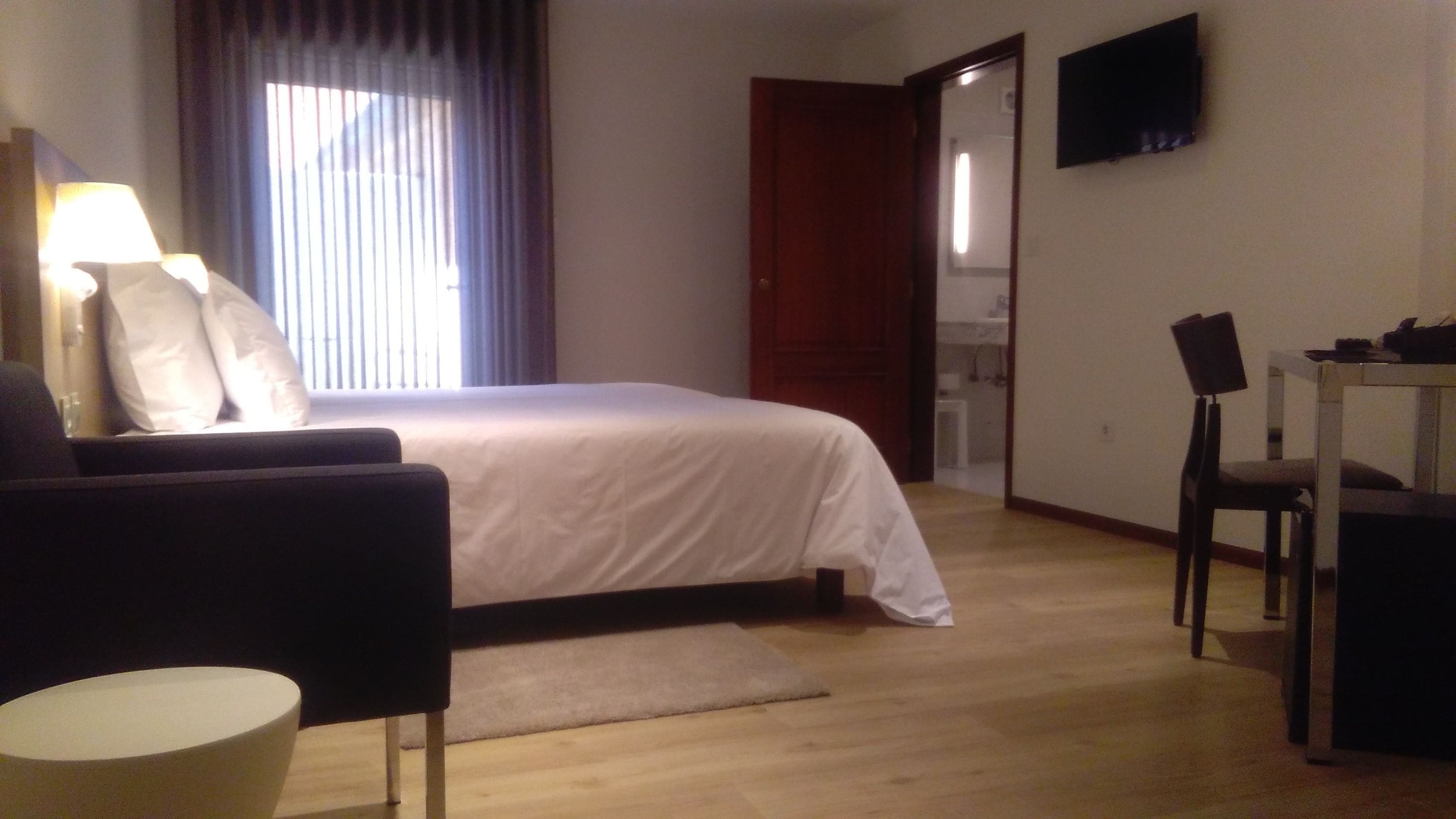 Een hotelkamer met een bed, een bureau, een stoel, een televisie en een lamp.